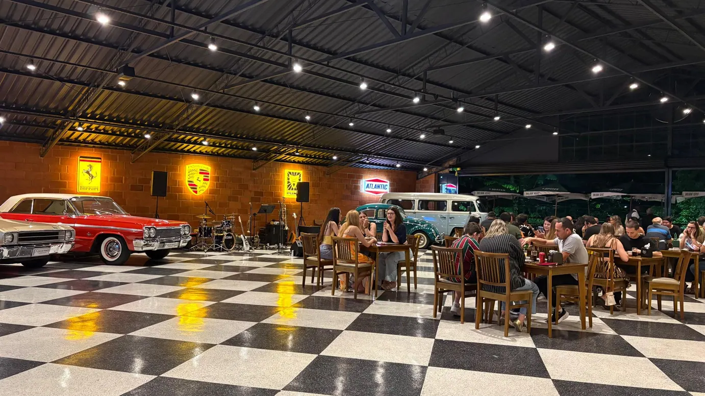Famílias à mesa no salão do Octano, com carro clássico ao fundo